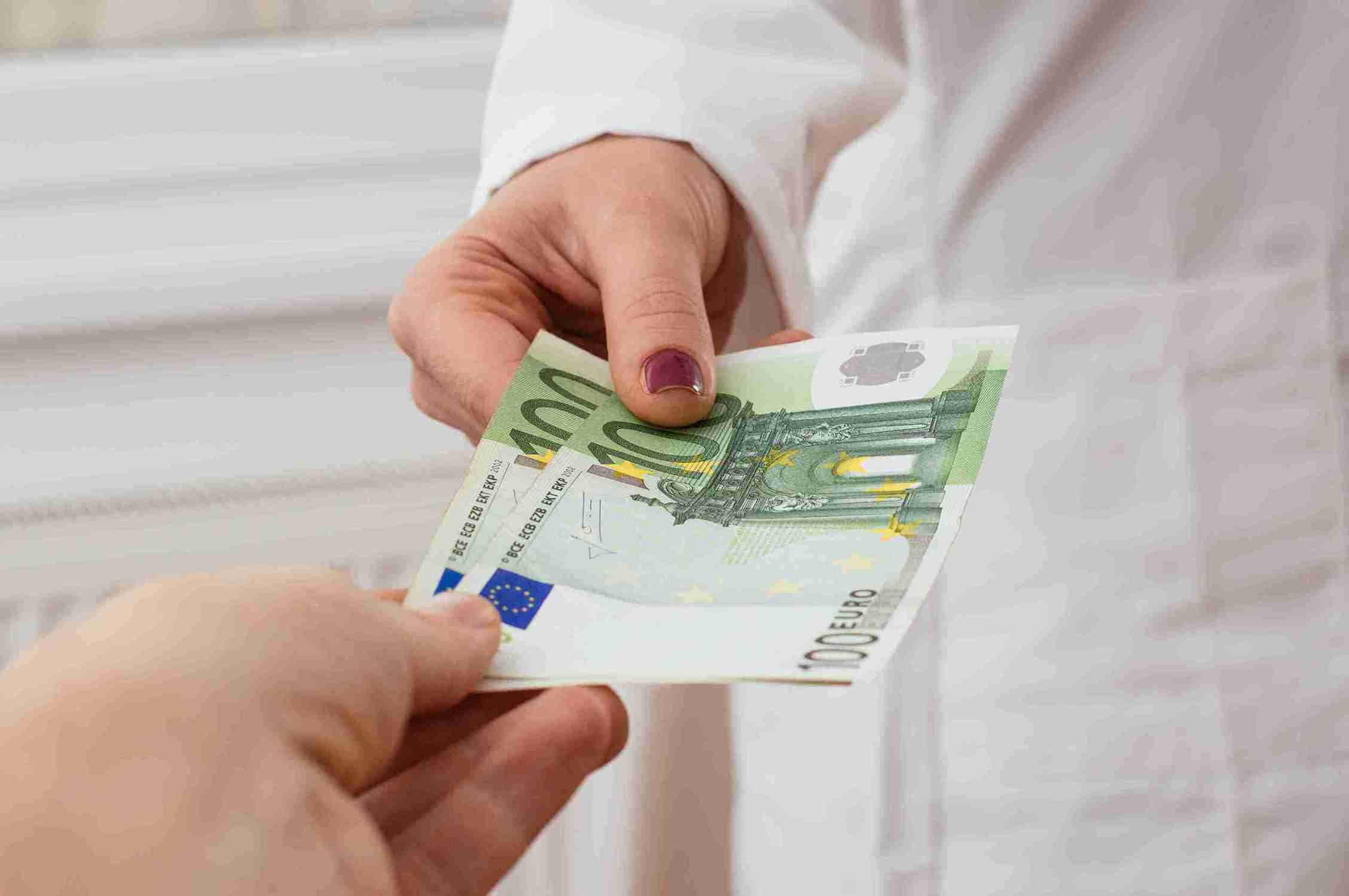 Arzt bekommt Geld von Patienten. Artikelbild für Haartransplantation Krankenkasse