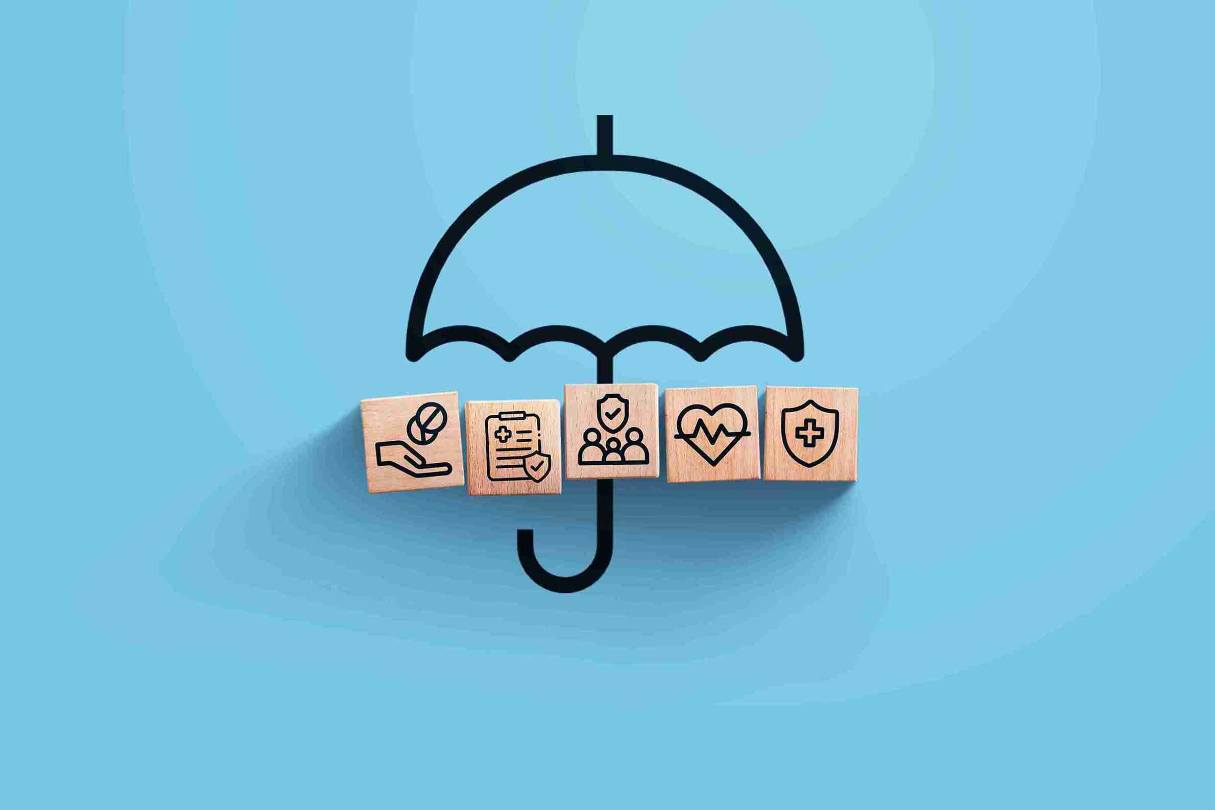 Concept image of health insurance coverage: a black umbrella shelters wooden blocks with medical and protection icons on a blue background, symbolizing the question: Does Insurance Cover Hair Transplant?