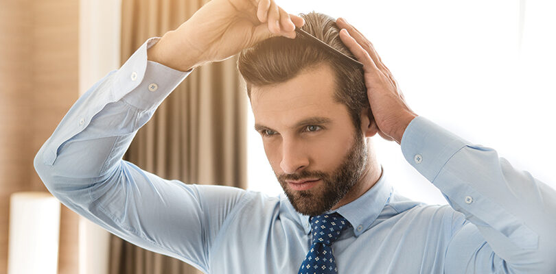 Uomo che si pettina i capelli con le mani, dettaglio dell'attaccatura frontale e della densità.